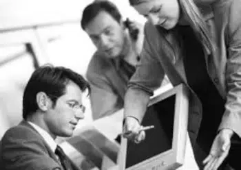 Dos hombres y una mujer directivos de empresa en una oficina delante de un ordenador